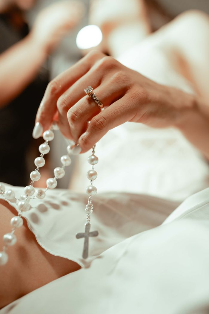 Close-up of bride holding a rosary, symbolizing faith and devotion on her wedding day.