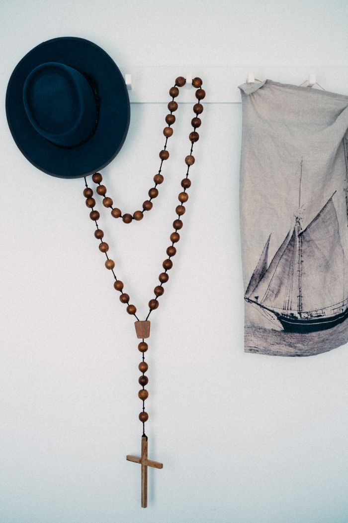 Blue hat and wooden rosary on a minimalist wall decor with nautical cloth.